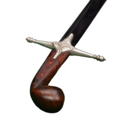 The Windlass Persian Scimitar is updated here with better, higher carbon steel over its original for improved overall performance. This scimitar  is a recreation of this iconic shamshir sword of the Middle East – this saber is not only light and nimble, but the curved blade is optimized for decisively deep cutting and quick slashes and in skilled hands the sword is a surprisingly capable piercing weapon which can strike its target at unpredictable angles. The blade is forged from well tempered 1075 high carbon steel and the hilt has a comfortable grip of well-polished wood with an enlarged pommel which neatly couches against the back of the hand for a sure grip. The crossguard is made from metal with an antiqued silvered appearance finish and the blade tang is dual-riveted into the grip for a solid overall construction.
Included with the sword is a scabbard of durable black leather with matching antiqued silvered metal fittings and hanging rings for wear.