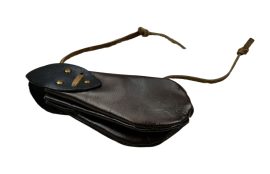 This Coin Purse is crafted from dark brown leather with tabs of black leather fitted into place with brass studs. Its accordion-like form is drawn closed with an interlaced leather drawstring.
