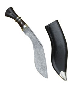 This Indian Khukuri has a large blade crafted from damascus steel. The bolster, pommel cap amnd grip rings are brass and the majority of the grip is formed from halves of carved and polished hardwood brass-riveted to the thick blade tang. The Kukri has a companion scabbard of carved wood fitted with a skin of black leather and a brass chape piece.
The Kukri has a well-deserved reputation as one of the most savage of chopping blades. Most bladed weapons of this size are not capable of severing limbs in a fell swoop, but this would not be unusual for the Khukuri – The elongated, forward sloping tip strikes with severe force in a manner more akin to a hatchet than a dagger.