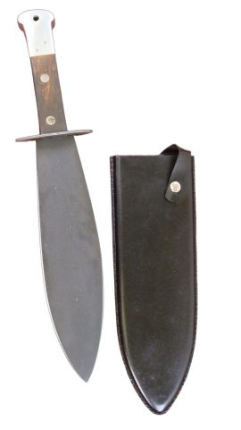 The psychological reaction of any man, when he first takes the smatchet in his hand is full justification for its recommendation as a fighting weapon. He will immediately register all the essential qualities of good soldier – confidence, determination, and aggressiveness. Its balance, weight and killing power, with the point, edge or pommel, combined with the extremely simple training necessary to become efficient in its use, make it the ideal personal weapon for all those not armed with a rifle and bayonet. – Capt. William E. Fairbairn
The Smatchet is one of the largest 20th century fighting knives, large enough that it is sometimes qualified as a short sword! Designed by military close-combat expert William E. Fairbairn, the Smatchet is purported to have been influenced by the trench swords used by the Royal Welch Fusiliers in WWI – who used a leaf-bladed short sword to great success in trench raids in the days before the battle of Messines. The Smatchet seems to be part bolo, part machete and part short, leaf-bladed sword . Like leaf-bladed swords, it chops and hacks with devastating ability due to its exaggerated mass along its striking edge. It also causes woefully wide wounds when thrust into the foe, as the tip quickly widens due to its low-tapered blade profile. The thick, heavy pommel is a capable weapon in itself, able to put down a man in a wild melee when time or space prevents turning the blade around.
Used by British and American Special Forces in World War II, the Smatchet made a good account of itself in the raids into Nazi-held Norway, where the big blade terrorized the Germans in the close-in house-to-house fighting and street raiding. The burly smatchet had an advantage over the smaller knives used by the foe and the psychological effect of the big knife gave as much confidence to its wielder as it sapped from the man facing it.
This Smatchet has a sharp blade of high carbon steel that is fully sharpened on one edge and half sharpened on the other. The blade is finished with a dull black finish and the guard is of steel. The thick, tang-sandwiching grip is of wood riveted to the tang with a thick steel pommel to cap it. A hole is drilled through the pommel to allow for a lanyard. Comes with a wood-core sheath covered in black leather with a retaining strap and button.