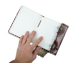 With its ensorcelled stone fitted within the cover, this handcrafted genuine leather journal the mystique of an alchemical tome an ancient codex or hidden diary – the pages inside are blank and await your hand to finish it.
This leather-bound handmade journal contains approximately 220 textured and natural-toned pages stitched to the binding. A gemstone emblazons the front cover and it is secured with a pair of antiqued brass hooks.
Please Note: The gemstone may vary somewhat in size and considerably in color.
Appx. 220 pages